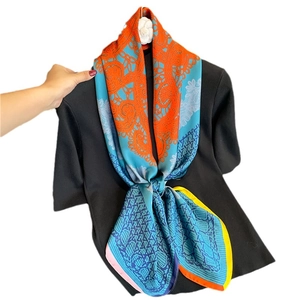 Luxury silk scarf with orange and blue chain patterns displayed on black top