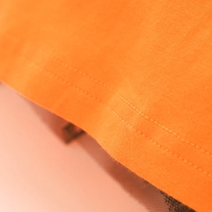 Detail der Doppelnaht und Textur auf orangefarbenem Strickstoff für Halloween Mädchenkleid