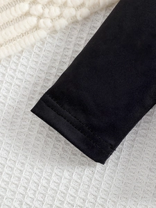 Détail de la double couture sur les poignets noirs en tricot pour ensemble bébé fille