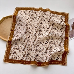 Détail d'un foulard carré avec motifs maison et arbre sur un tissu soyeux de qualité