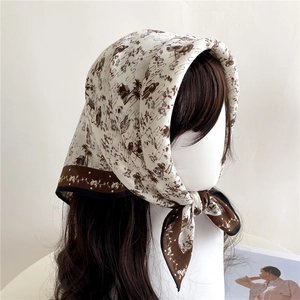 Détail d'un foulard imprimé vintage avec motifs classiques sur tissu beige et bords ondulés