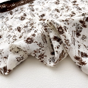 Détail de l'imprimé vintage maison et arbre sur foulard en soie crème et bord brun
