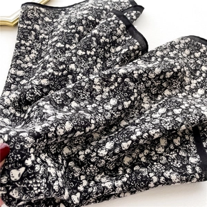 Close-up of floral print silk scarf featuring delicate black and white patterns and fine edges