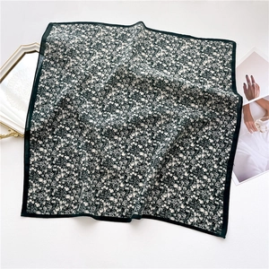 Flat lay of vintage floral silk scarf with delicate white flowers on dark background