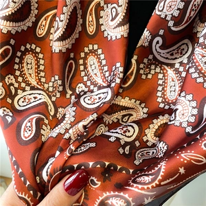 Deep orange paisley silk-like square scarf with elegant drape and smooth satin texture