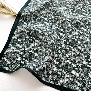 Detailed texture of dark green floral silk scarf with vintage botanical fruit patterns