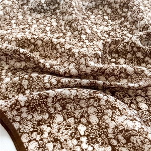 Detailed macro view of vintage floral silk scarf with fine brown hem and drape texture