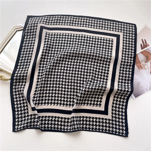 Close-up of houndstooth silk scarf on a grey textured background with a vintage gold mirror