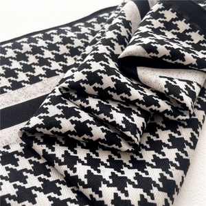 Detailed close-up of classic black and white houndstooth pattern scarf with striped borders