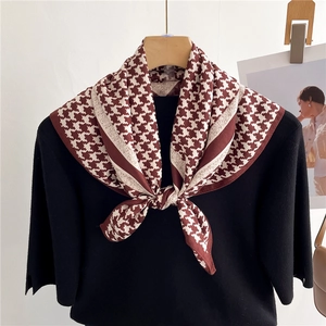 Classic houndstooth silk scarf in brown and white tied on a wooden hanger with knits