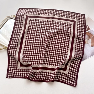 Detail of burgundy houndstooth silk-like scarf with elegant folded texture