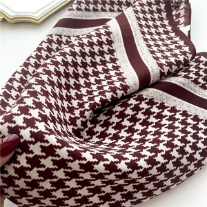 Macro detail of houndstooth scarf showing wine red textile texture and soft fabric