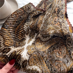 Détail macro d'un foulard élégant avec motif cachemire et texture plissée soyeuse