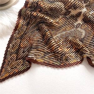 Gros plan du foulard en soie plissé avec motifs cachemire vintage dans les tons bruns