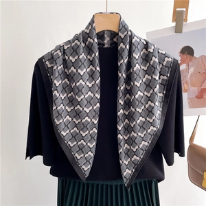Détail d'un foulard carré à motifs floraux porté sur un haut noir et jupe plissée