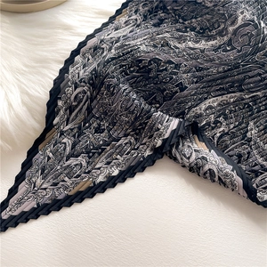 Vue détaillée d'un foulard en soie plissé avec motif paisley et bordures ondulées