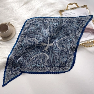 Détail d'un foulard en satin bleu marine à motif paisley et texture plissée chic