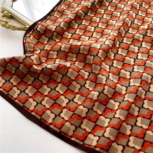 Vue détaillée d'une écharpe vintage à carreaux floraux orange et marron sur surface blanche