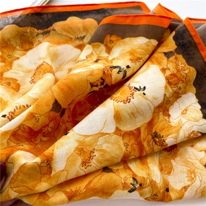 Detailed texture of floral square scarf with vibrant orange blooms and silk-like finish
