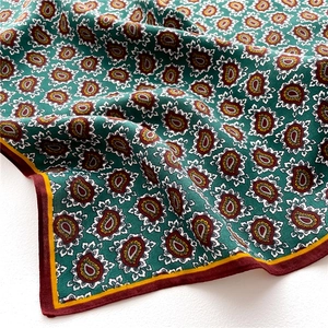Close-up of green paisley silk scarf with red striped edges and soft woven texture