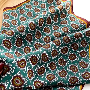 Close-up of emerald green scarf with vintage paisley print and burgundy border