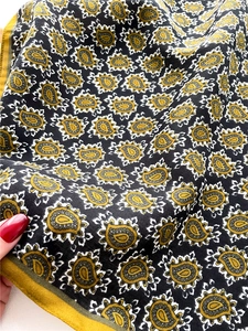 Detail of sunflower paisley square scarf with vibrant yellow hem and soft texture