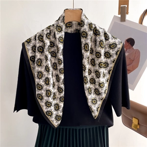 Elegant paisley floral pattern silk-feel scarf styled on a black mannequin with chic outfit