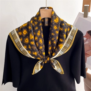Detail of leopard print silk-like scarf with yellow tones and geometric border accents