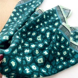 Detailed view of green leopard print scarf featuring fine twill texture and border