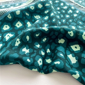 Macro detail of silk-like scarf featuring deep green herringbone and abstract dot patterns