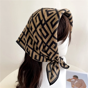 Close-up of geometric pattern silk scarf with vintage gold and black print detail