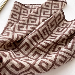 Detail of soft silk-like square scarf with brown geometric monogram and fine edges