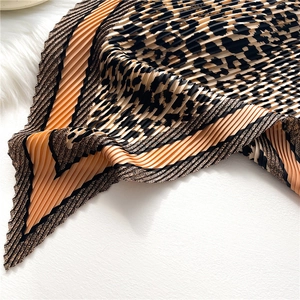 Detail of leopard print pleated silk scarf with orange borders and accordion texture