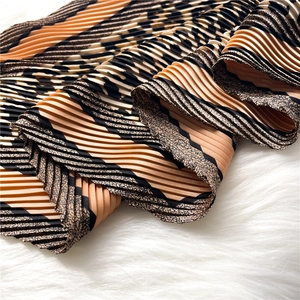 Macro detail of pleated leopard print scarf with orange and black diagonal stripe pattern
