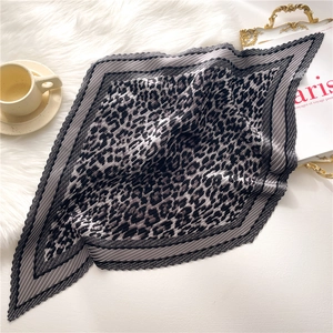 Detailed view of pleated leopard print silk scarf with grey striped borders on plush decor