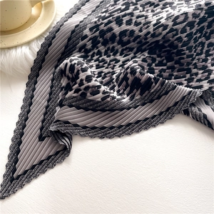 Macro shot of accordion pleated leopard print silk scarf with chic wavy edges and stripe detail