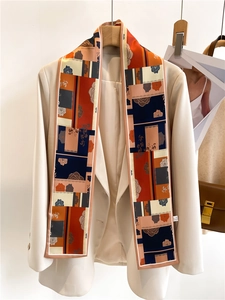 Détail d'un foulard twilly à motifs porté comme cravate élégante sur un tailleur beige