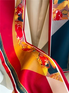 Gros plan détaillé montrant la texture soyeuse et les motifs sur un foulard en soie rouge