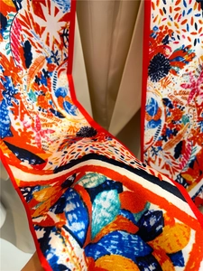 Gros plan sur un foulard en soie aux imprimés abstraits et bordures rouges précises