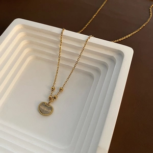 Élégant collier en acier titane doré avec pendentif cadenas en œil de chat sur escalier