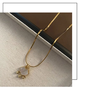 Détail de chaîne serpent dorée avec pendentif serrure Ruyi rétro et nacre blanche