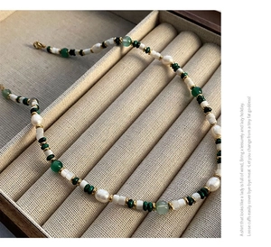 Close-up of shell agate necklace with baroque pearls and green beads in jewelry box
