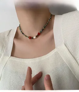 Détail du collier vintage avec perles turquoise vertes, agate rouge et perle blanche sur modèle