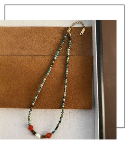 Détail du collier fait main avec perles de turquoise, agate rouge et une perle blanche