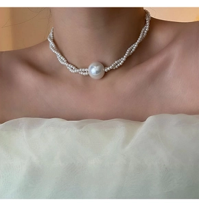 Detail einer eleganten dreireihigen Perlenkette mit einer großen zentralen Muschelperle