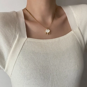 Elegante collana in titanio dorato con pendente a lucchetto in conchiglia bianca su modella