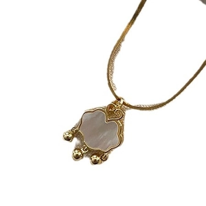 Collana in acciaio al titanio dorato con conchiglia naturale e tre ciondoli
