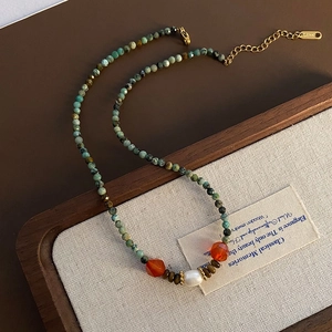 Collier fait main avec pierres naturelles vertes, agate orange et perle blanche sur lin