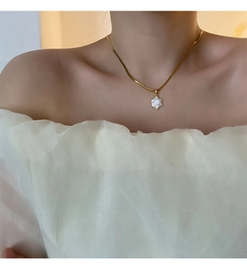 Detail of a gold turtle pendant necklace with a white hexagonal shell on a female model
