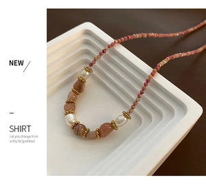 Détail d'un collier de perles roses avec pierres naturelles sur un plateau en céramique